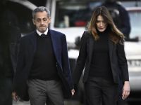 France's former president Nicolas Sarkozy (L), with his wife Carla Bruni-Sarkozy, leaves his residence to present himself to La Sante Prison for incarceration on a five-year prison sentence after being convicted of criminal conspiracy over a plan for late Libyan dictator Moamer Kadhafi to fund his 2007 electoral campaign, in Paris, on October 21, 2025. Sarkozy begins five-year prison term in Paris over Libyan campaign funding scandal
