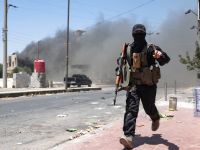 Heavy smoke rises as a member of Bedouin and tribal forces runs during clashes with Druze fighters in Syria's southern city of Sweida, despite an announcement by the Syrian interim president of an "immediate ceasefire" on July 19, 2025. (Photo by OMAR HAJ KADOUR / AFP) Jihadist Omar Omsen