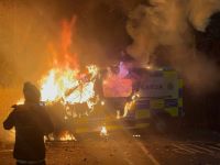 Onlookers film a police vehicle burning as a demonstration outside a hotel housing asylum seekers turns violent in Saggart, south-west of Dublin in Ireland on October 21, 2025. (Photo by AFP) Dublin