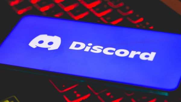 The Discord logo on a cell phone screen resting on top of a laptop keyboard. (Shutterstock) Discord